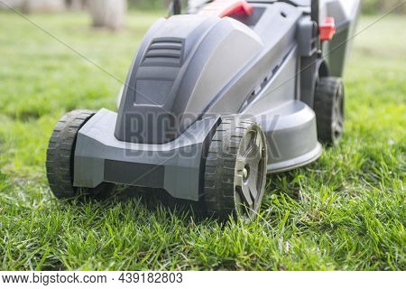 Lawn Mower Working In The Garden. Lawn Mower On Green Grass.