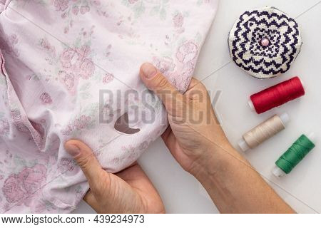 Woman Hand Holding Torn Cloth Seamy Side Showing Hole On White Background With Needle Bar And Thread