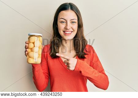Young brunette woman holding bottle with boiled potatoes smiling happy pointing with hand and finger 