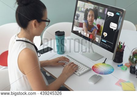 Caucasian girl using computer for video call, with smiling elementary school pupil on screen. communication technology and online education, digital composite image.