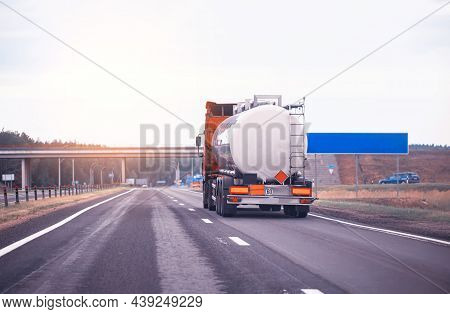 Truck With Semi-trailer Tanker Transports Dangerous Goods On The Highway On The Background Of Sunset