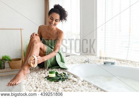 Millennial Woman In Towel Sitting Near Bubble Bath, Making Anti Cellulite Or Lymphatic Leg Massage W