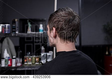 Portrait Occiput Of A Guy Of Caucasian Appearance With Dark Hair In A Black Sweatshirt Against The B