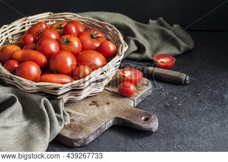 Fresh Red Tomatoes In Whicker Basket On Black Background.