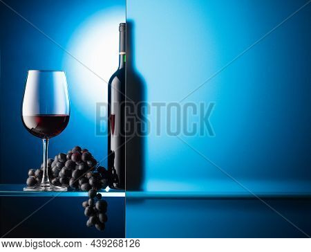 Bottle And A Glass Of Red Wine With A Bunch Of Blue Grapes. The Still Life Is Partially Covered By A