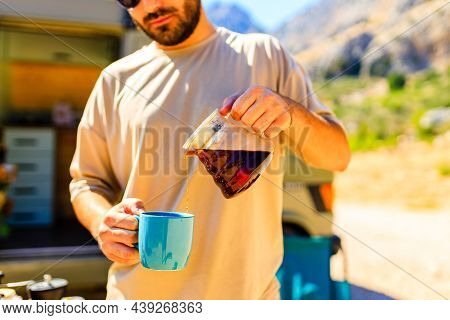 Man In Charming Trailer House Makes Coffee Outdoors In Mountains In Summer Sunny Day