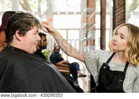 Hairstylist trimming hair of the customer in a beauty salon