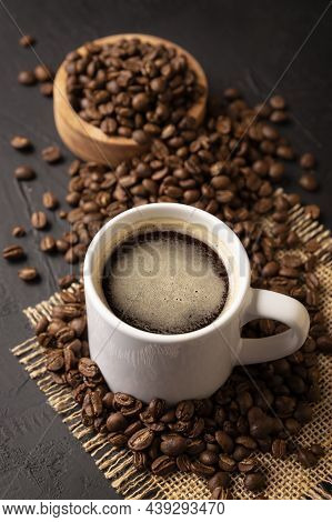 Coffee Beans Scattered On A Rustic Black Table And White Lungo Cup With Hot Coffee Drink. Close Up I