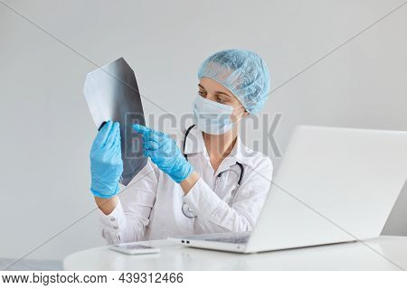 Young Adult Doctor Sitting On Front Of Laptop Screen And Showing X Ray To Camera, Gown, A Medical Ca
