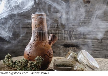 Old Brown Steamung Bong And Open Cannabis Grinder With Chopped Marijuana Weed And Medical Cannabis B