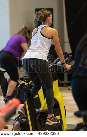 Rimini, Italy - September  2021: Girl Having Workout At Gym With Indoor Exercise Bike.
