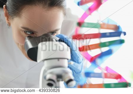 Woman Scientist Looking Through Microscope Near Dna Molecule Mockup In Lab. Scientific Genetic Resea