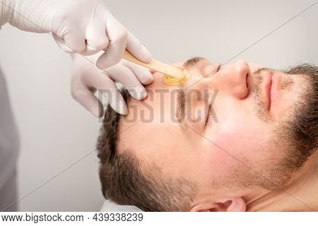 Beautician Applying Wax Paste Between Eyebrows During The Procedure Of Waxing In The Beauty Salon