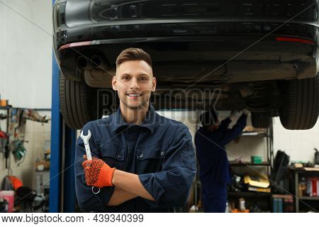 Portrait Of Professional Mechanic With Wrench At Automobile Repair Shop