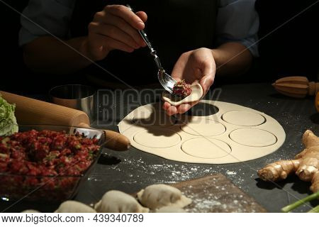 Woman Putting Gyoza Filling In Center Of Dough Wrapper At Grey Table, Closeup