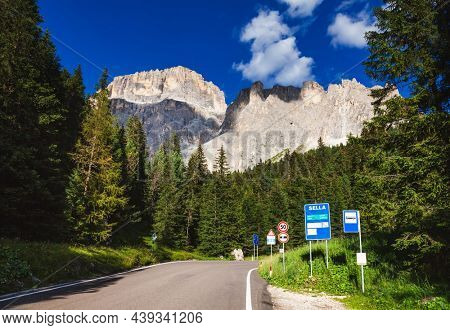 Scenic road to the Sella Pass in Dolomites, South Tyrol (Sudtirol, Alto Adige), Italy, with high rock wall of Sella group seen in background