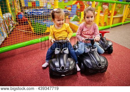 Two Siters Rides On A Plastic Cars In Indoor Play Center.
