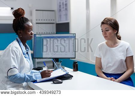 African American Therapist Doctor Discussing Disease Symptoms With Woman Patient Writing Medication 