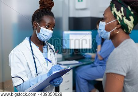 African American Therapist Doctor Wearing Protective Face Mask Discussing Sickness Symptoms With Sic