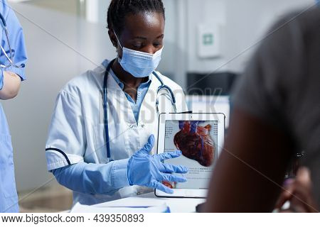 African American Cardiologist Doctor Showing Heart Radiohraphy To Sick Patient Using Tablet Explaini
