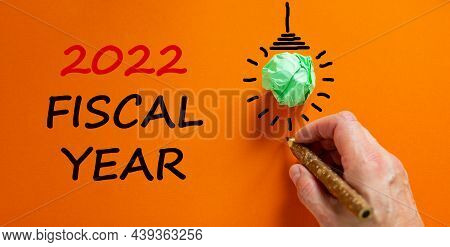 2022 Fiscal New Year Symbol. Businessman Writing Words '2022 Fiscal Year', Isolated On Beautiful Ora