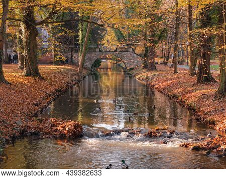 Manor Park In The City Of Ilowa In Poland. A Small, Narrow River. There Is An Ancient Stone Bridge F