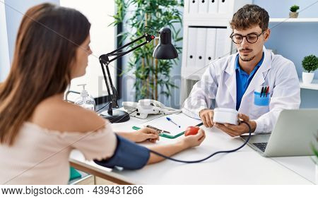 Man and woman wearing doctor uniform having medical consultation using tensiometer at clinic