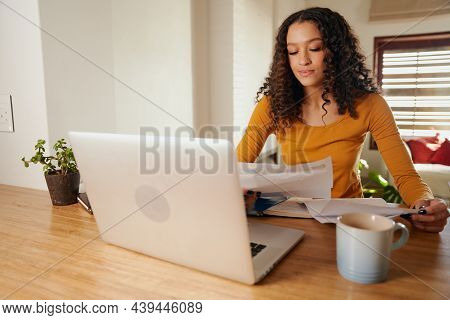 Multi-cultural Female Paying Bills From Home. Young Professional Remote Working With Laptop In Moder
