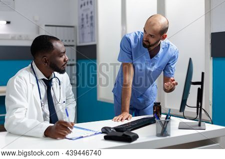 African American Physician Doctor Analyzing Clinical Documents Discussing Healthcare Treatment With 
