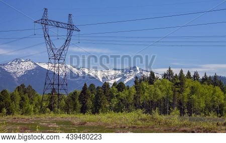 Metal Supports And Wires Of High-voltage Highway In The Siberian Taiga Against The Background Of Mou