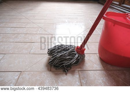 Mop And Red Bucket Of Cleaning On The Tiled Floor Ready To Clean Close-up.  Cleaning Services. Home 