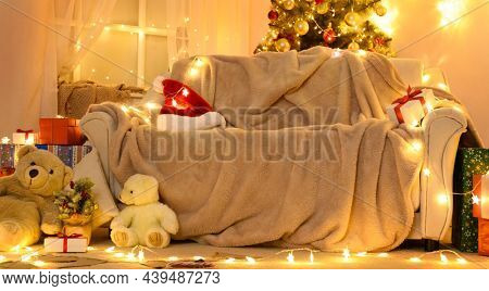 Festive Home interior - wew year or christmas decoration. At night, the room glows with festive lights. A lots of gifts and decorations. Winter holiday concept