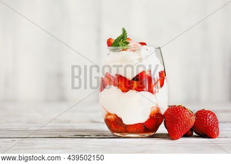 Healthy Breakfast Of Strawberry Parfait Made With Fresh Fruit, And Yogurt Over A Rustic White Table.