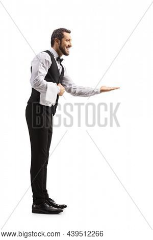 Full length profile shot of a polite elegant waiter gesturing with hand and waiting tip isolated on white background