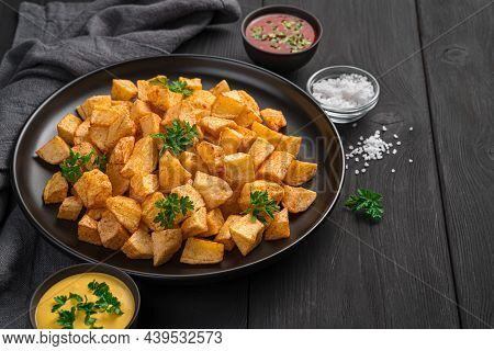 Patatas Bravas With Hot Sauces On A Black Background. Tapas, A Spanish Snack.