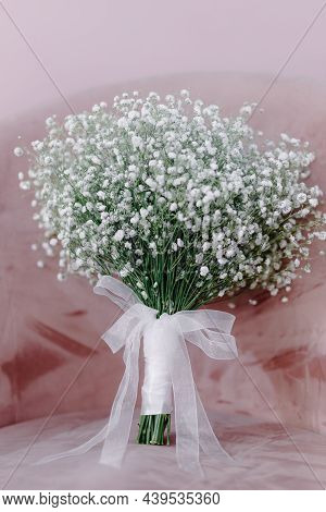 Bridal Bouquet Of Flowers With White Ribbon Stands On A Pink Chair. High Quality Photo