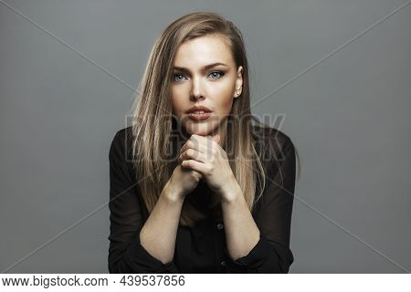 Serious Young Woman Sits At The Table With Her Hands Folded. Beautiful Blonde. Career And Business. 