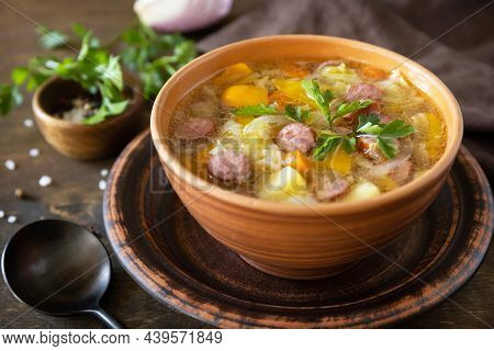 Czech Food: Traditional Zelnacka Cabbage Soup With Sausages And Vegetables In A Bowl On Rustic Woode