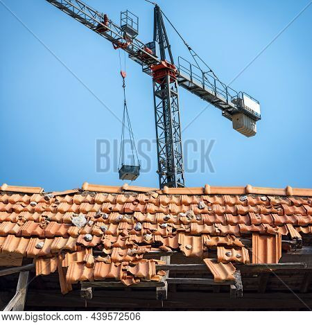 Gray Crane And Closeup Of A Damaged Roof With Terracotta Orange Tiles (pantiles, Coppo In Italian La
