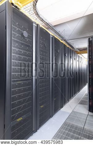 Data center with multiple rows of fully operational server racks. modern cloud computing technology concept.