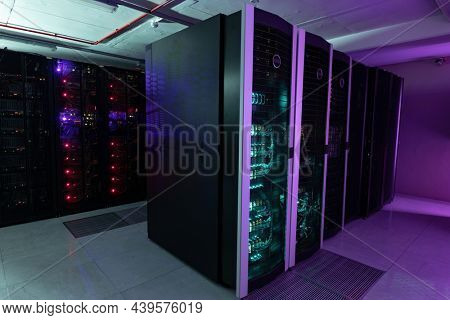 Data center with multiple rows of fully operational server racks. modern cloud computing technology concept.