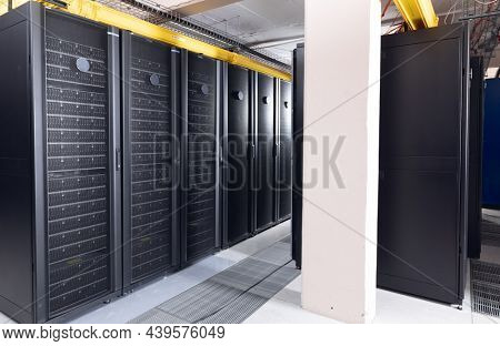 Data center with multiple rows of fully operational server racks. modern cloud computing technology concept.