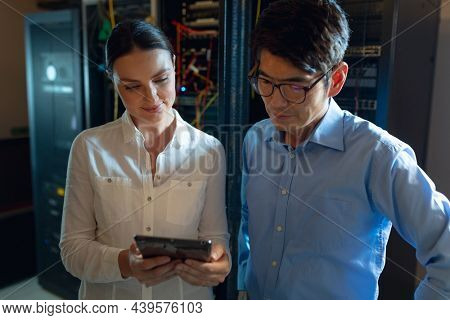 Diverse male and female engineers using digital tablet in computer server room. database server management and maintenance concept