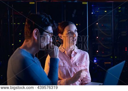 Diverse male and female engineers using laptop in computer server room. database server management and maintenance concept