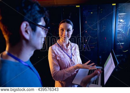 Diverse male and female engineers using laptop in computer server room. database server management and maintenance concept
