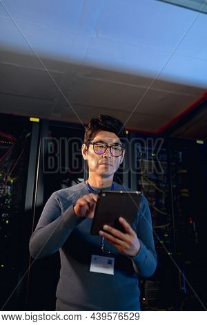 Asian male engineer using digital tablet in computer server room. database server management and maintenance concept