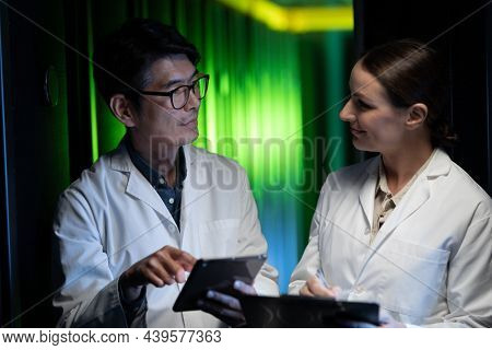 Diverse male and female engineers wearing aprons using digital tablet in computer server room. database server management and maintenance concept