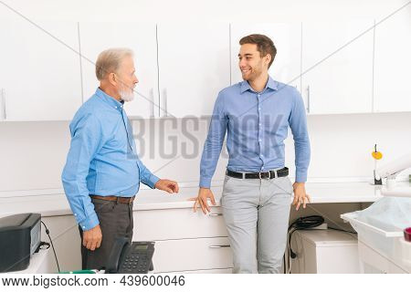 Happy Gray-haired Senior Handsome Male And Cheerful Young Man In Matching Shirts Chatting Together I