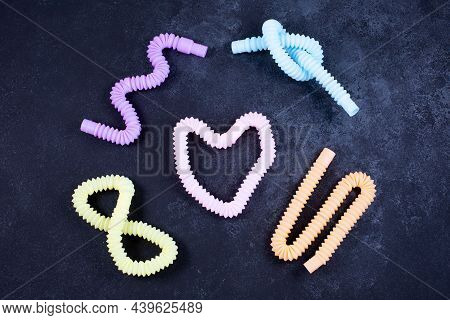 Multicolored Bright Tubes On Black Background. Anti-stress Sensory Figet Plastic Toy.