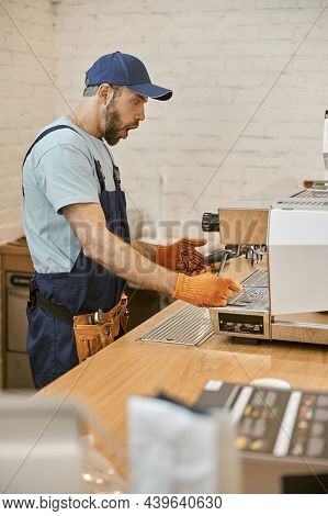 Shocked Repairman Fixing Coffee Machine In Cafe